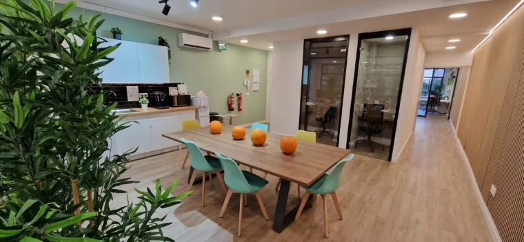 Zona de café de Language Avenue, con la mesa grande y las aulas acristaladas al fondo
